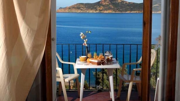 A balcony with a table set for breakfast, overlooking a coastal view with mountains in the background. - Hôtel Restaurant Le Filosorma (Galeria)