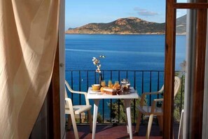 A balcony with a table set for breakfast, overlooking a coastal view with mountains in the background. - Hôtel Restaurant Le Filosorma (Galeria)