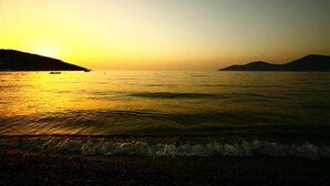 A beach at sunset with calm waters and distant hills. - Hôtel Restaurant Le Filosorma (Galeria)