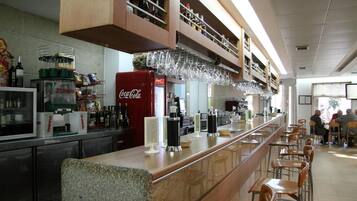 Una zona de bar con mostrador, estantes con botellas y un refrigerador de Coca-Cola.
