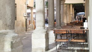 Un espacio de descanso al aire libre con columnas de piedra y mesas de madera.
