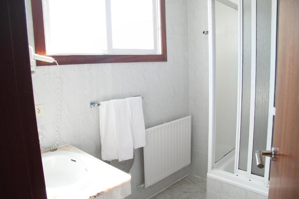 A bathroom with a bathtub, a shower, and a window providing natural light.