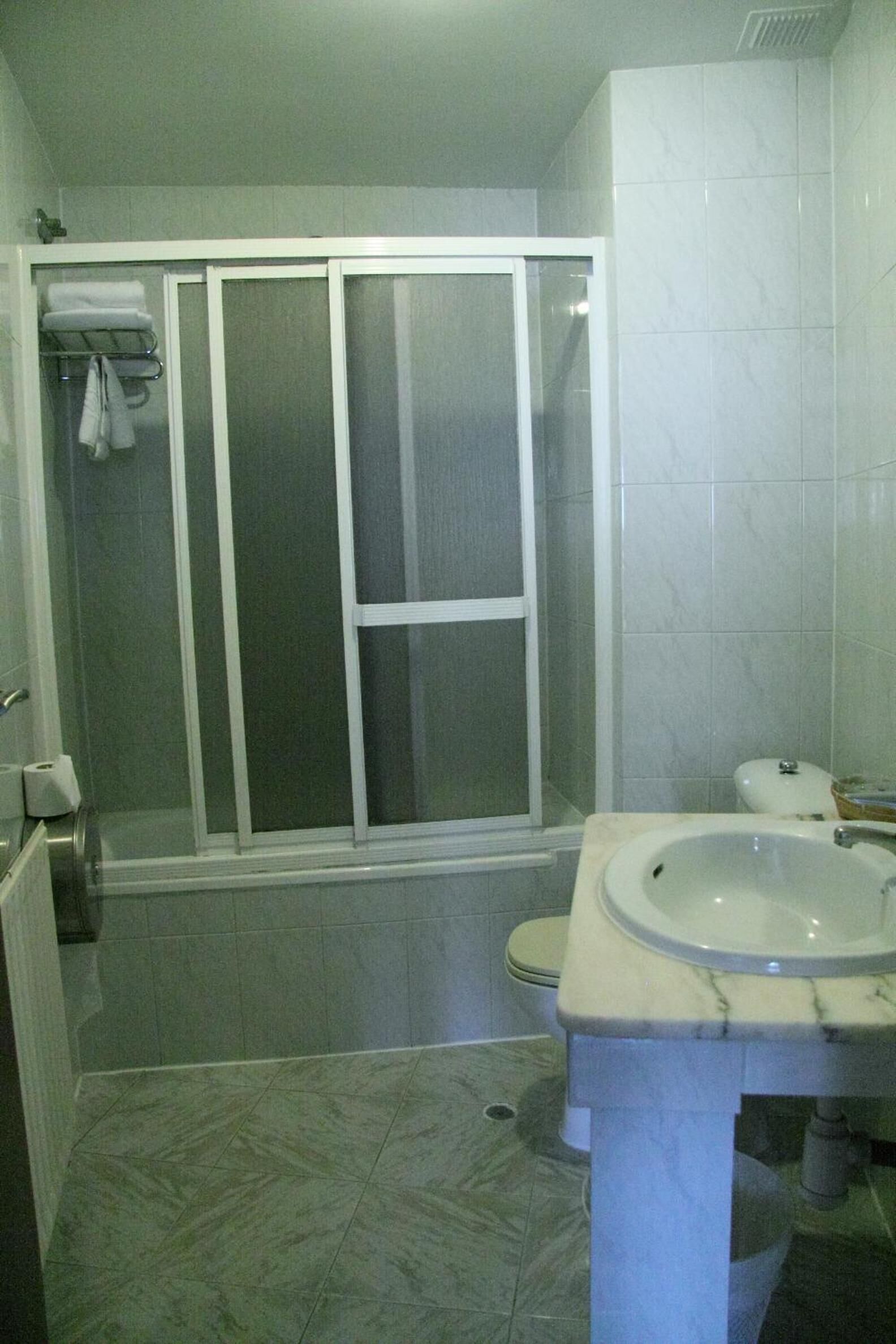 Un baño con cabina de ducha, inodoro y lavamanos.
