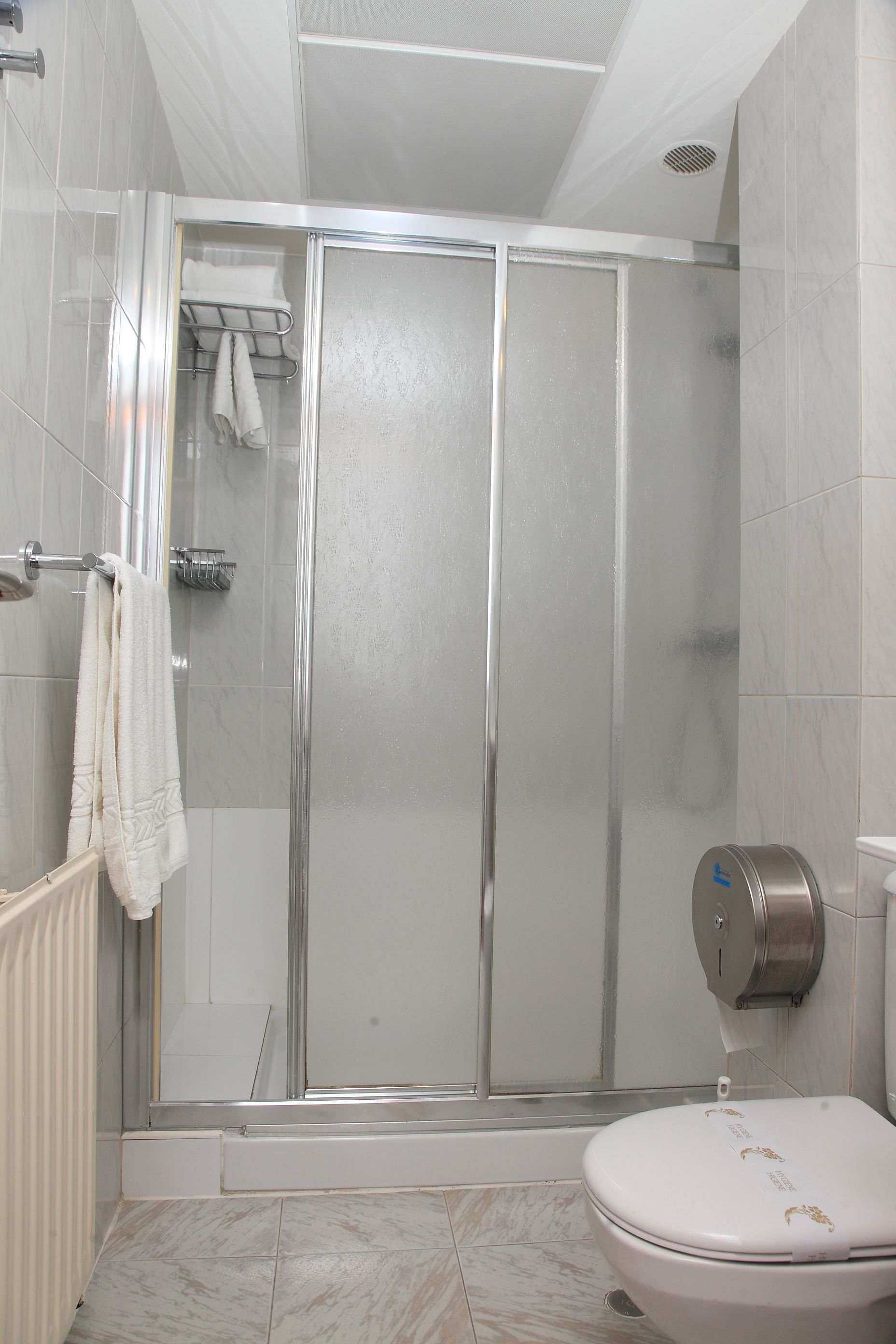 Une salle de bain avec une douche à parois de verre, des toilettes et un porte-serviettes avec des serviettes.