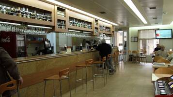 A bar area with stools, a counter, and shelves with bottles and glasses.
