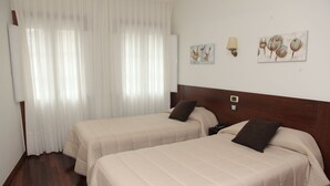 Habitación de hotel con dos camas, cabecero de madera, lámpara de pared y una obra de arte.