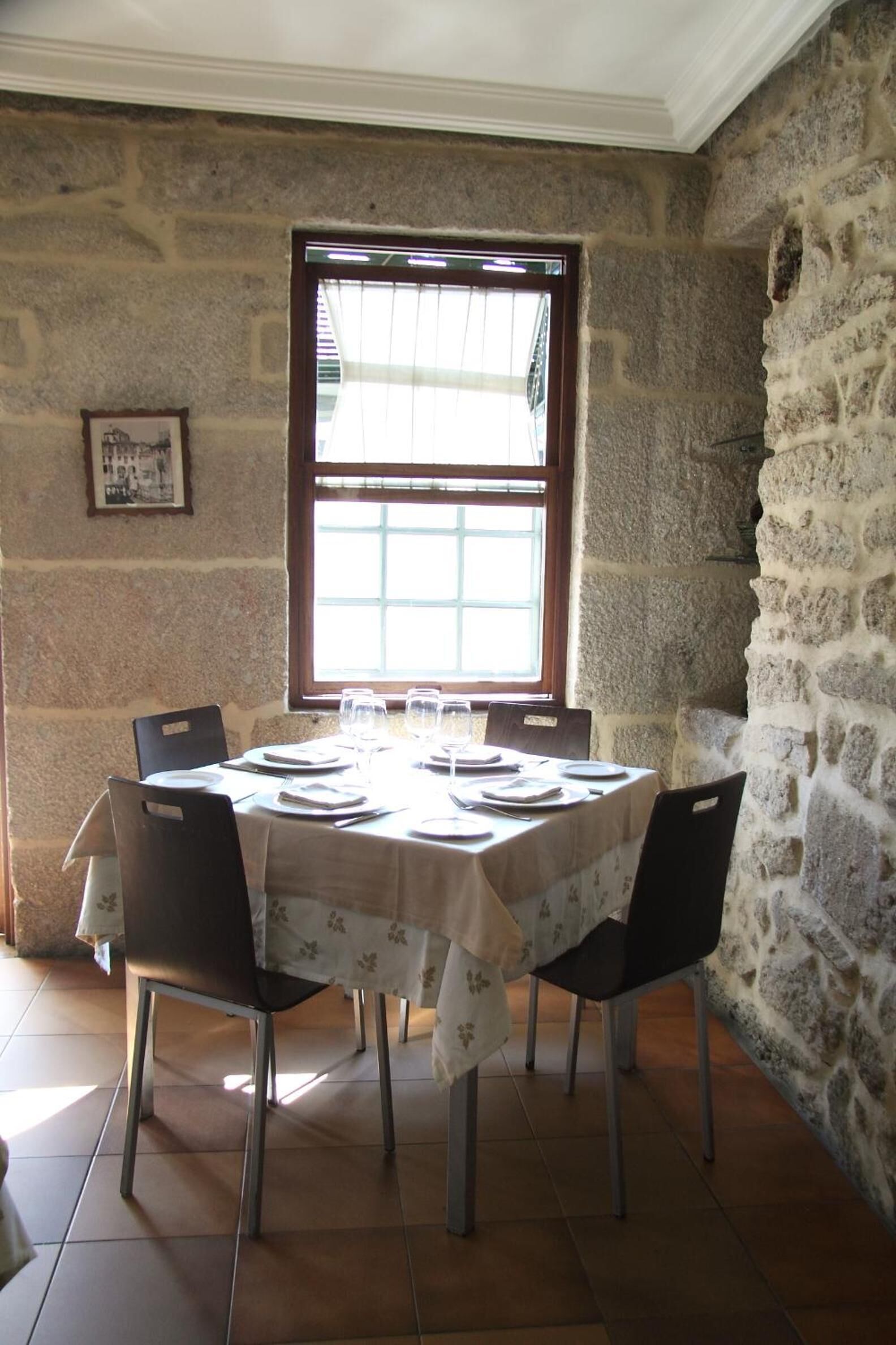 A dining area with a stone wall, a large window, and a table set for four.