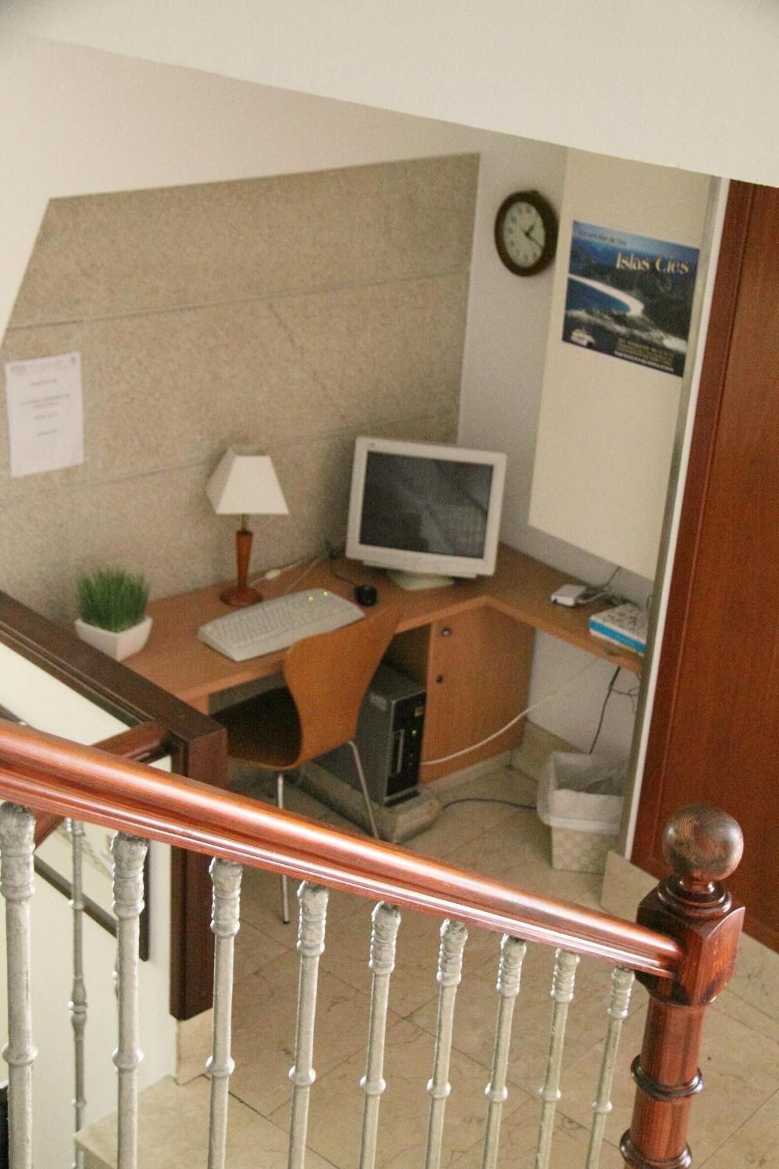 A home office with a desk, computer, lamp, and a clock on the wall.