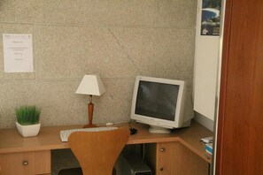 A small office cubicle with a desktop computer, a lamp, a keyboard, and a potted plant. - Hotel Restaurante Rúas (Pontevedra)