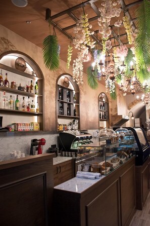 A bar area with shelves of bottles, a coffee machine, and a pastry display.