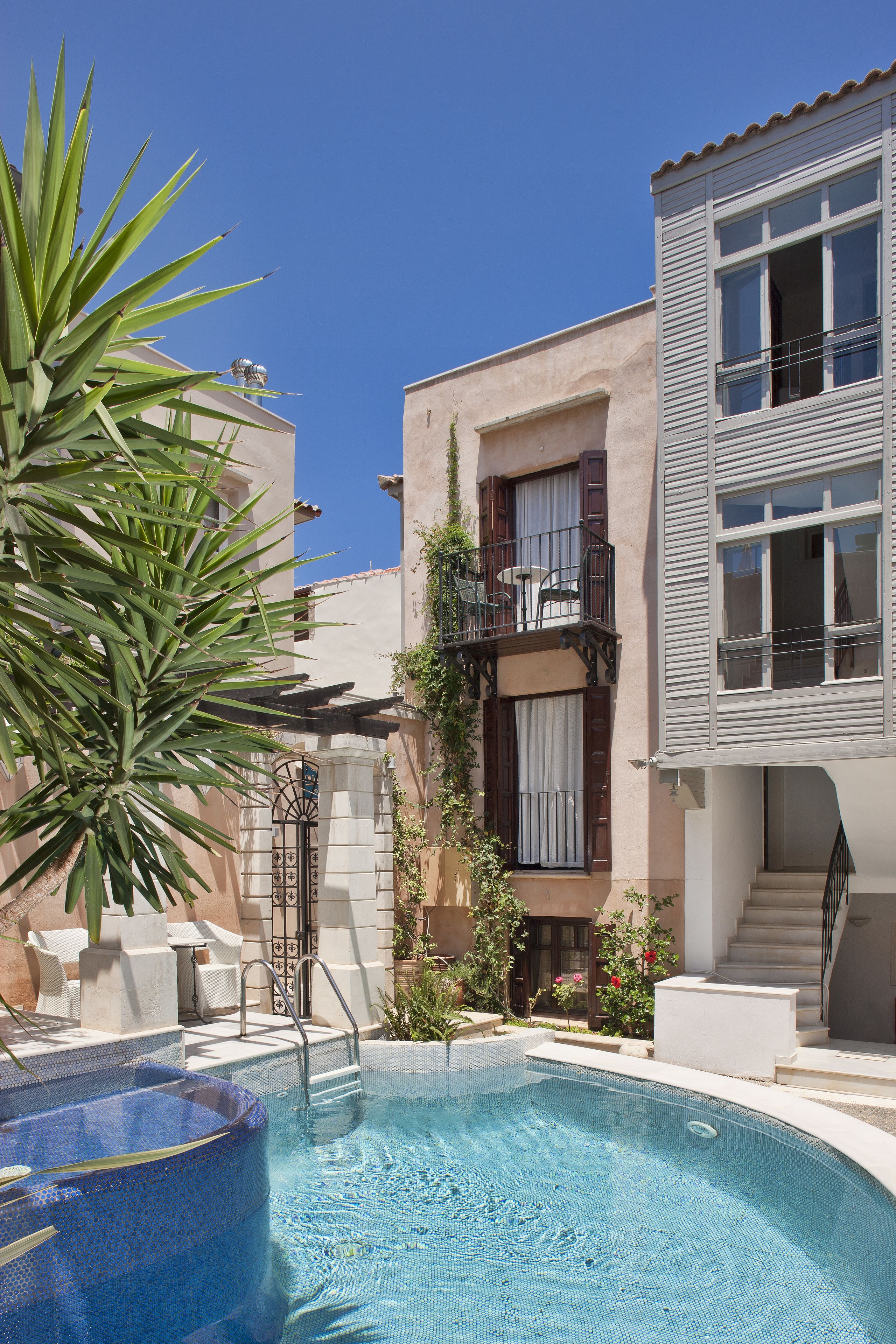 Ein Poolbereich mit Whirlpool, einer Treppe zu einem Balkon und einer Palme.