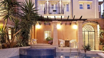 A pool area with a hot tub, lounge chairs, and a pergola.