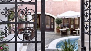 Ein Innenhof mit Pool, Außenmöbeln und einem Gebäude mit Rundbogenfenstern.