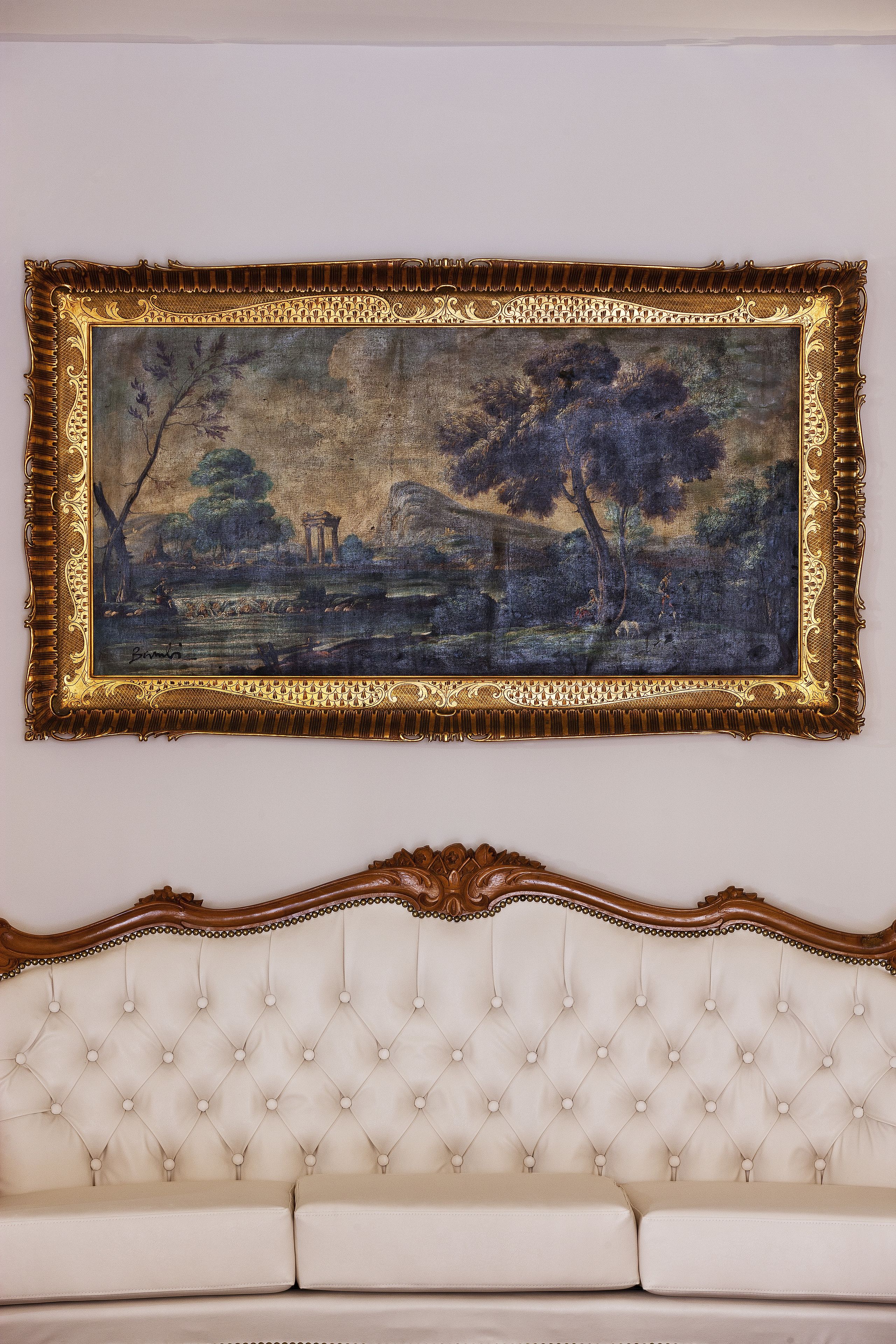 Ein gerahmtes Landschaftsbild über einer gesteppten Couch.