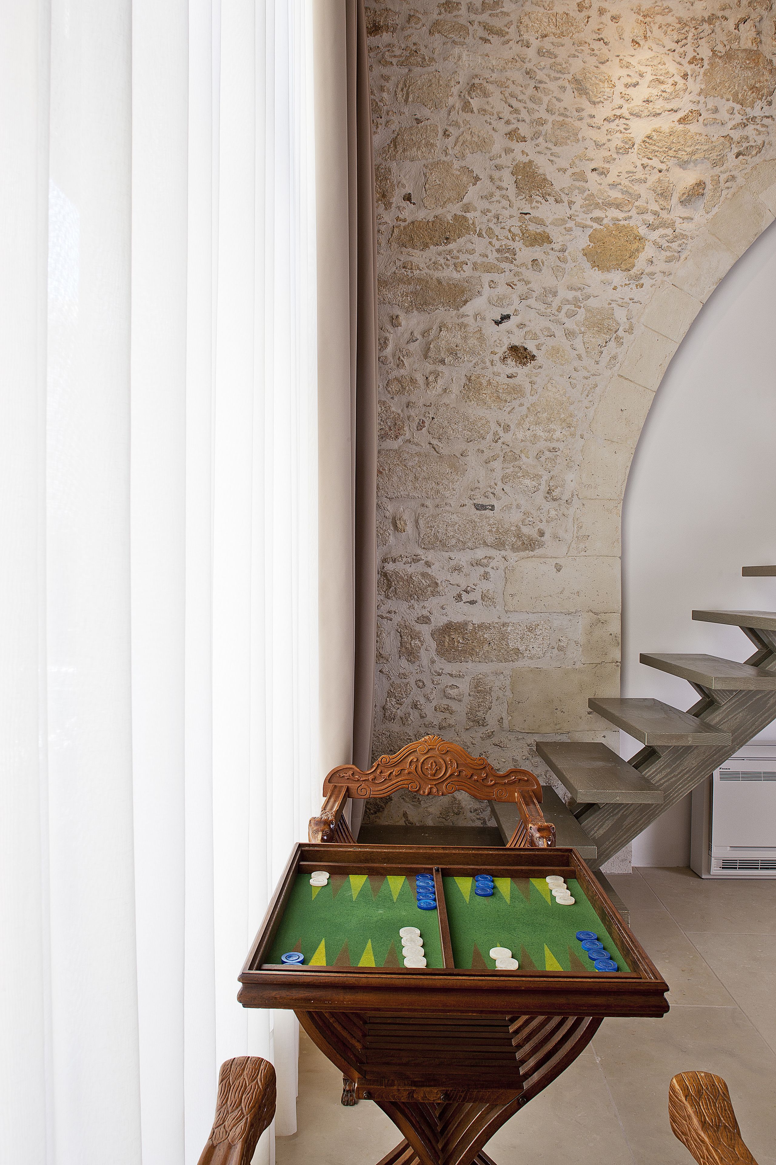 Ein Billardtisch mit grüner Spielvliesbahn und Holzrahmen, vor einer Steinwand mit Treppe platziert.