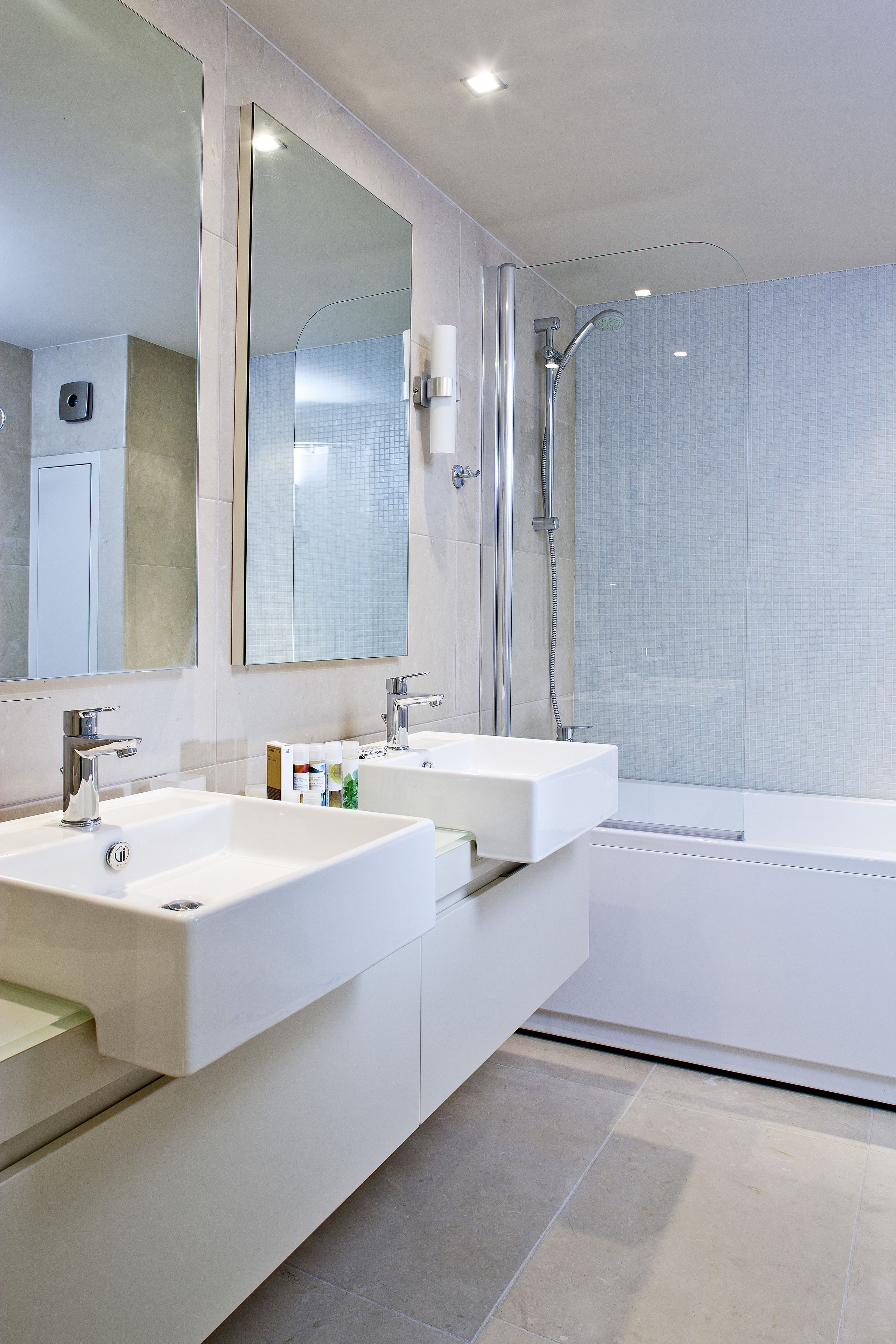 A modern bathroom with two sinks, a large mirror, and a shower area.