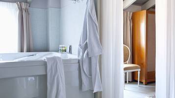 Ein Badezimmer mit Badewanne, einem Sessel und einem Paar Hausschuhen auf dem Boden.