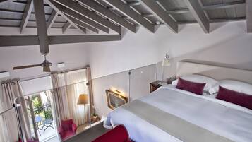 A bedroom with a large bed, a ceiling fan, and a view of the outside.