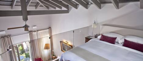 A bedroom with a large bed, a ceiling fan, and a view of the outside.