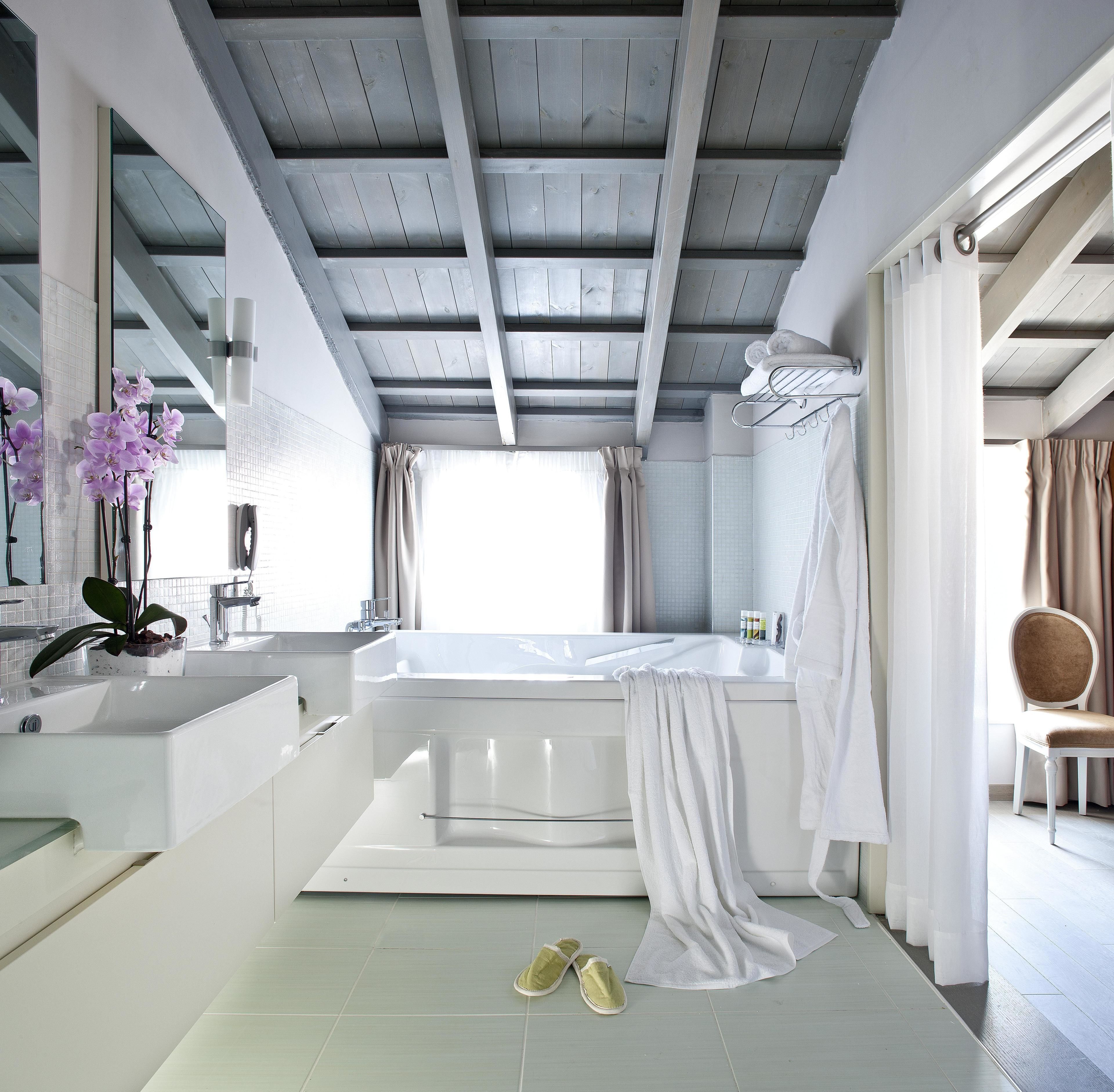 Un baño moderno con una bañera, un espejo grande y un lavabo.