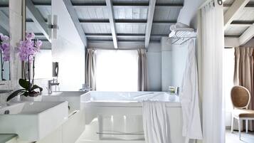 Un baño moderno con una bañera, un espejo grande y un lavabo.