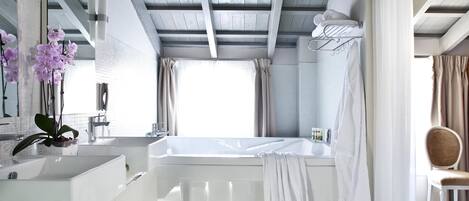 Un baño moderno con una bañera, un espejo grande y un lavabo.
