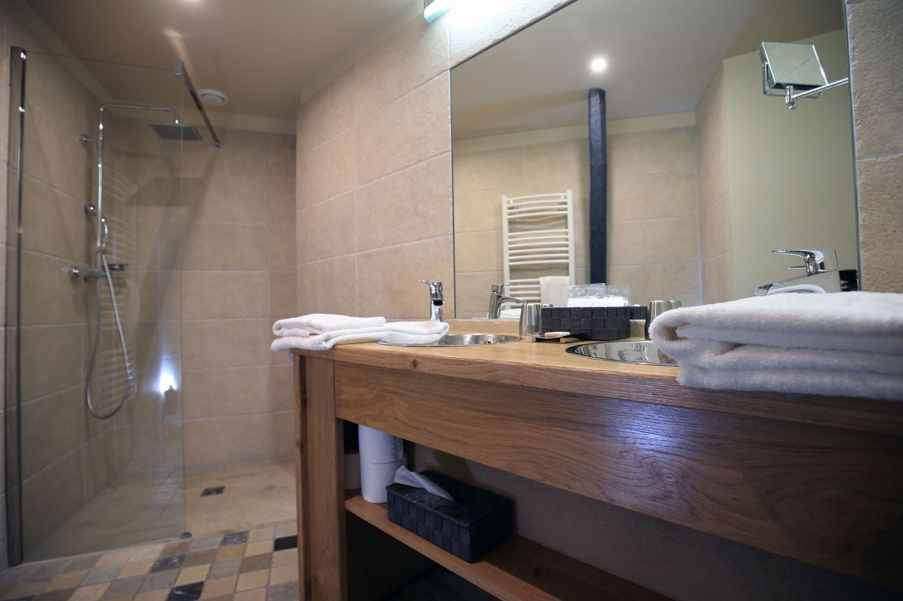 A modern bathroom with a shower, a wooden vanity, and a large mirror.