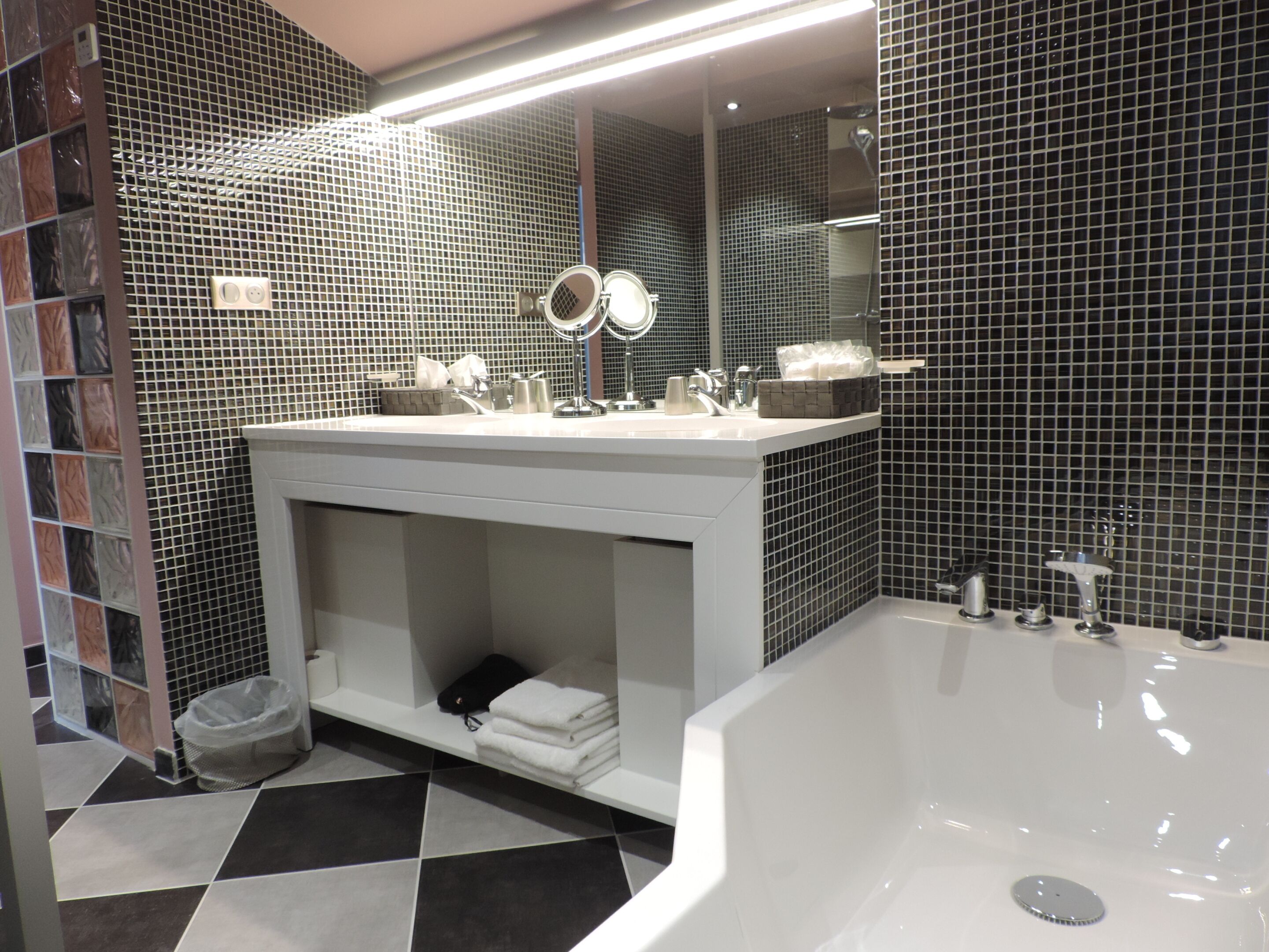 Un baño moderno con una bañera grande, un tocador con espejo y un salpicadero de azulejos.
