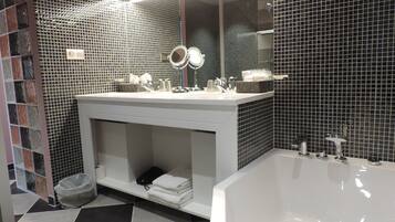 Un baño moderno con una bañera grande, un tocador con espejo y un salpicadero de azulejos.