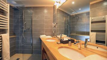 Een moderne badkamer met twee wastafels, een douchecabine met glazen wanden en een grote spiegel.