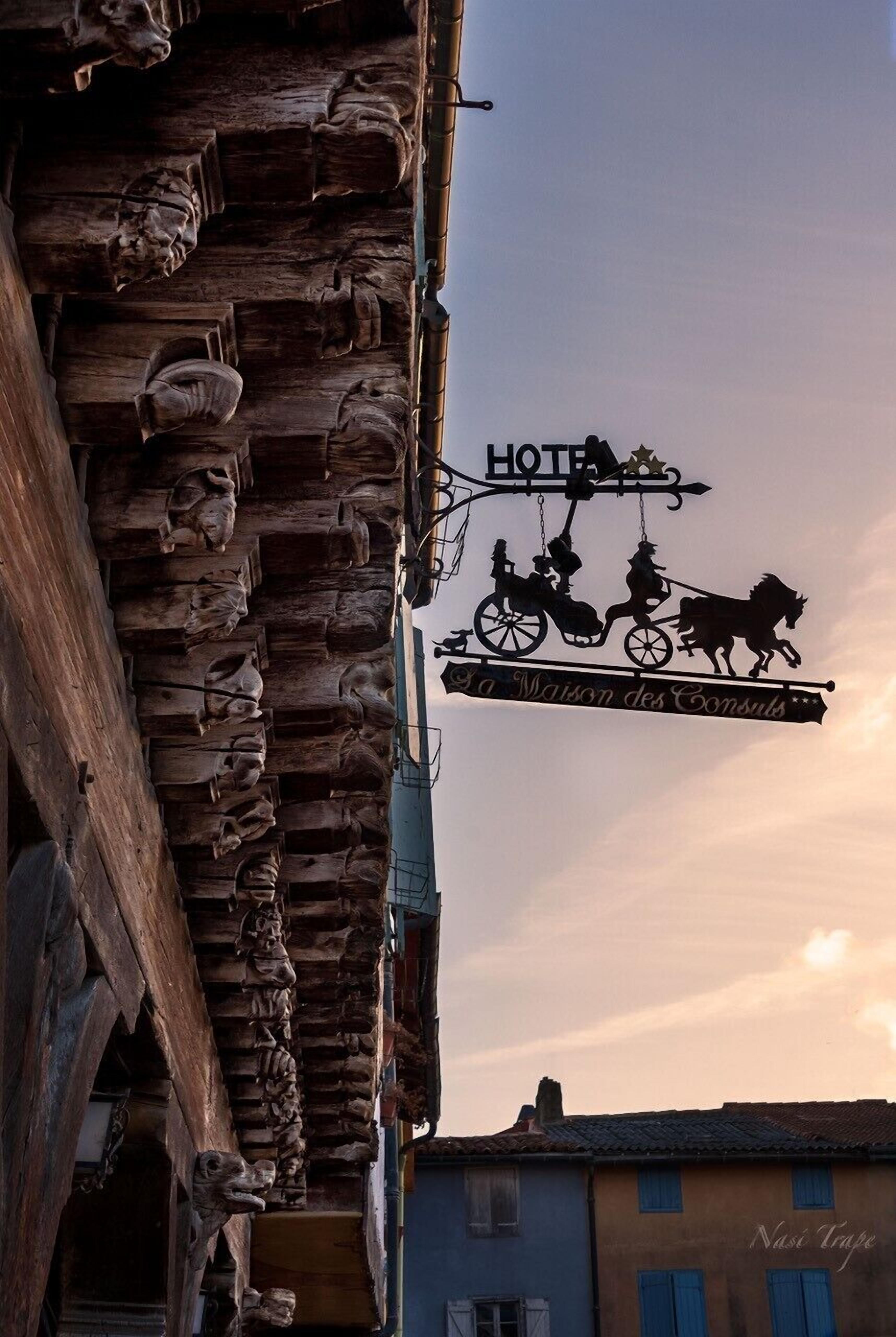 Ein Hotelschild mit einer Silhouette einer Kutsche und dem Schriftzug "La Maison des Consuls".