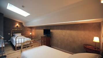 A hotel room with two beds, a desk, a TV, and a skylight.