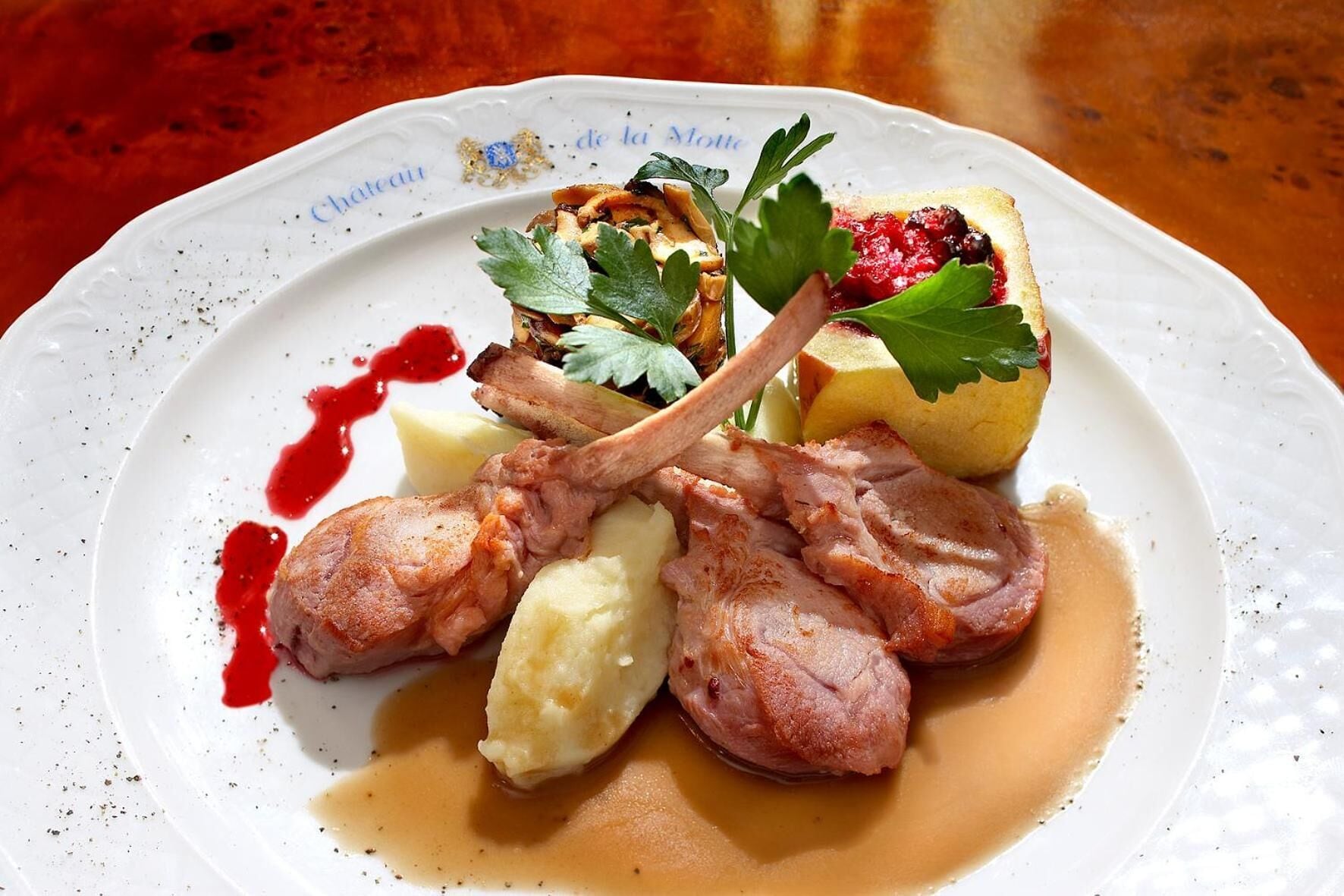 A plate of food with lamb chops, mashed potatoes, and a berry compote.
