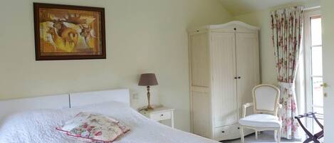Un dormitorio con cama, armario, silla y un cuadro en la pared.