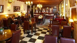 Een restaurant met houten meubels, geruite vloer en kroonluchters.