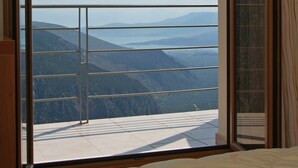 A bedroom with a large window offering a view of mountains and a lake.