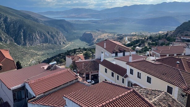 A mountainous town with terracotta-roofed buildings and a valley below.
