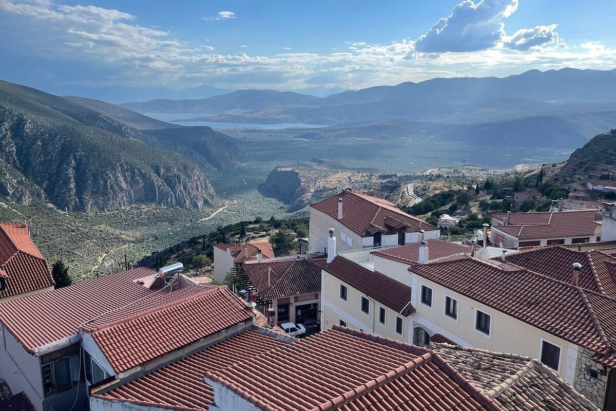 Une ville de montagne aux bâtiments aux toits de tuiles rouges, surplombant une vallée.