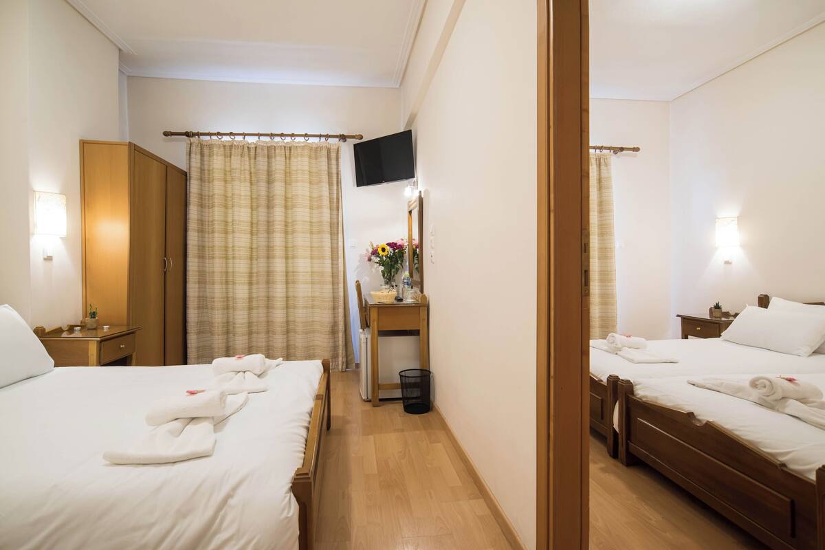 Une chambre d’hôtel avec deux lits, un bureau, une télévision et un miroir.