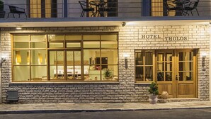 A hotel with a stone facade, multiple windows, and outdoor seating.