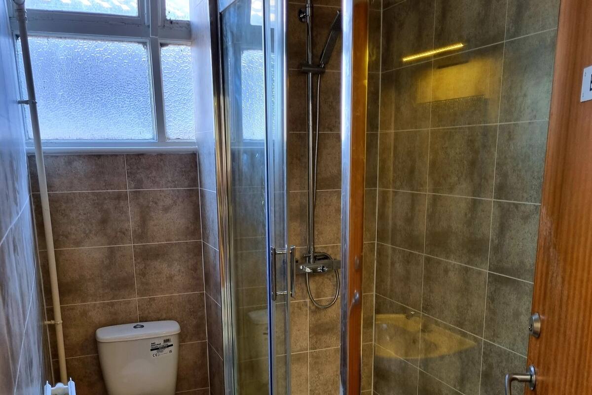 A compact bathroom with a glass-enclosed shower, a toilet, and a bathtub.