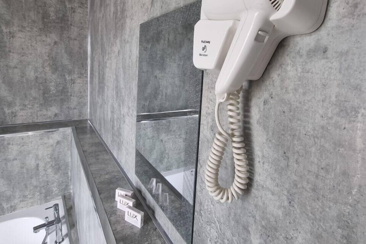 A bathroom with a hairdryer mounted on the wall, a towel rack, and a mirror.