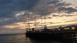 Eine Steg, der sich ins Wasser erstreckt, mit einem Gebäude und einem leuchtenden Neonzeichen.