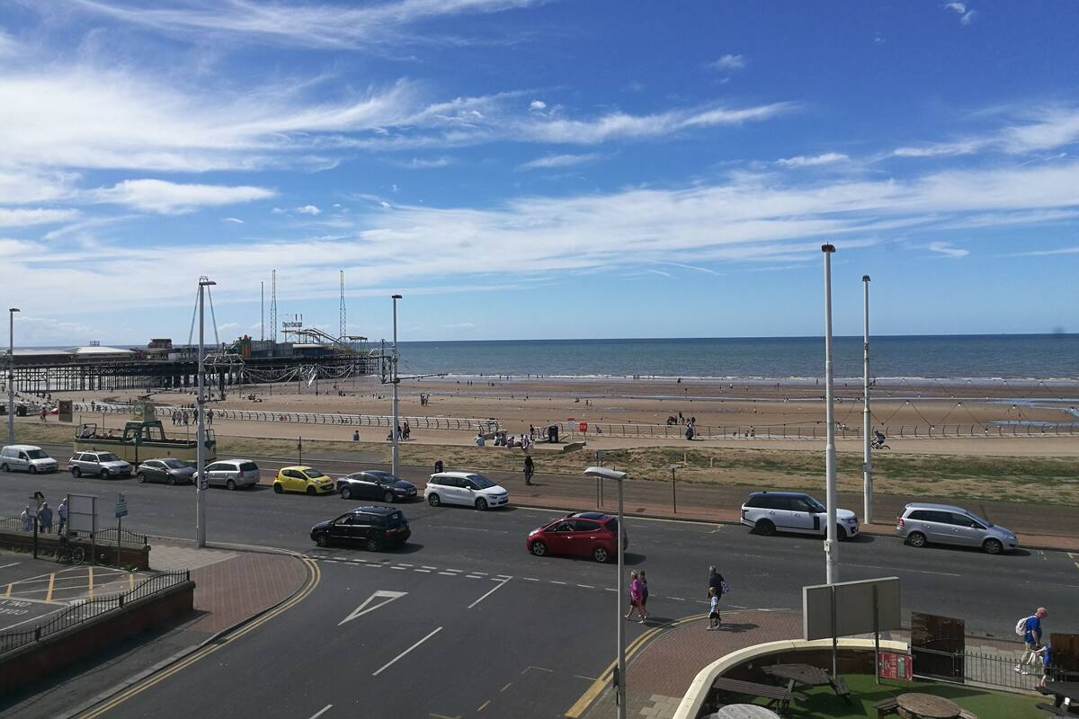 A coastal road with a beach and pier in the background.