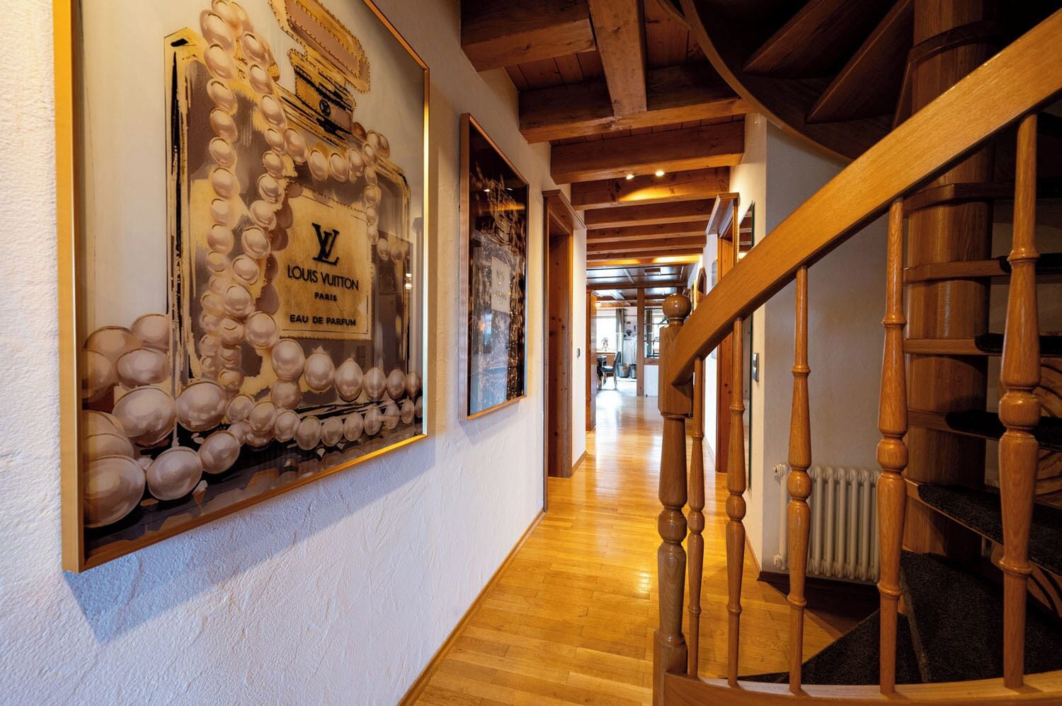 A hallway with a Louis Vuitton perfume display, wooden flooring, and a wooden staircase.