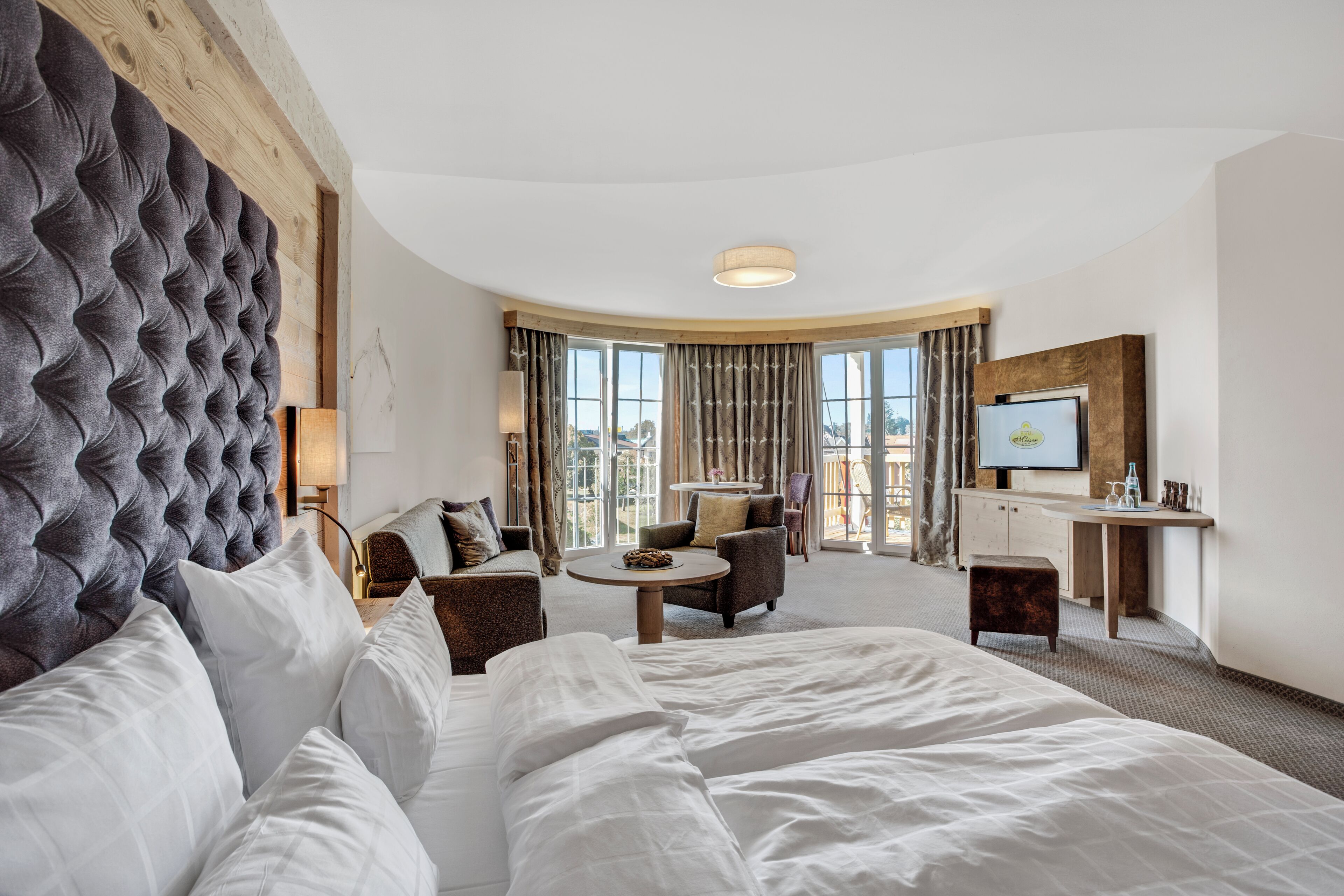 A hotel room with a large bed, a sofa, a desk, and a TV.