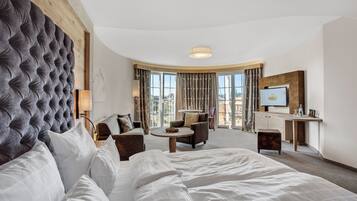 A hotel room with a large bed, a sofa, a desk, and a TV.