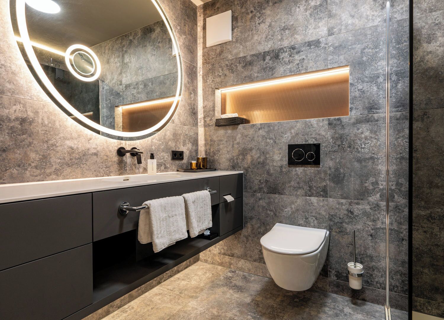 A modern bathroom with a large mirror, a vanity with a sink, a toilet, and a towel rack.