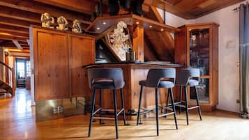 Ein Holzinterieur mit Barbereich, drei Barhocker und einer Treppe, die zu einer weiteren Ebene führt.