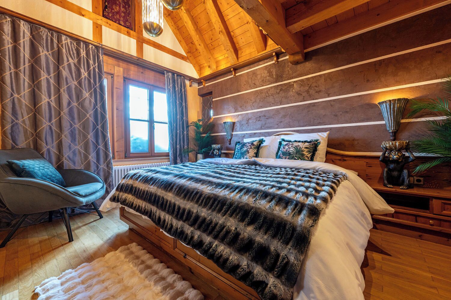Un dormitorio acogedor con una cama grande, una silla y techo de madera.